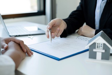 a real estate agent with a house model is talking to clients about buying home insurance. home insurance concept.