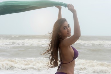 beautiful asian woman in swimsuit bikini at the beach by the sea. wind blow from the sea feel good.