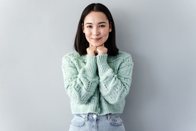 beautiful girl in a knitted sweater on a background of blank, gray wall. cute brunette isolated on a gray background.