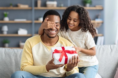 happy little daughter giving present to her dad