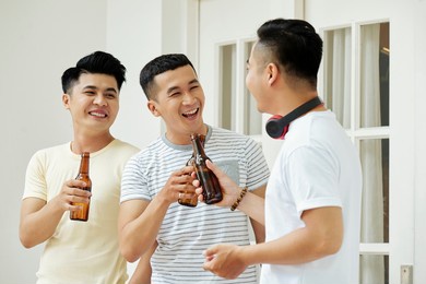 group of asian men having fun together while drinking beer at home