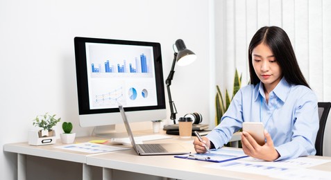 asian women sit at their desks and calculate financial graphs showing results about their investments, plan a successful business growth process.