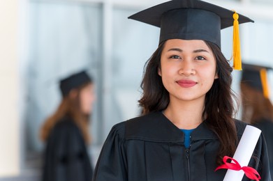 group of graduates asian student in academic gown and graduation cap holding diploma