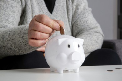 elderly woman counting last coins from piggy bank, sitting depressed and worried at home. concept of savings, insurance and retirement.