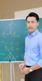 asian senior high school male teacher teach math online through mobile phone in classroom