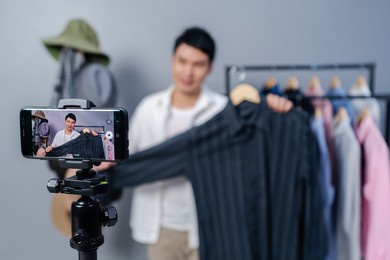 young man selling clothes and accessories online by smartphone live streaming, business online e-commerce at home