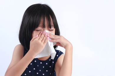sick little asian girl wiping or cleaning nose with tissue isolated white background