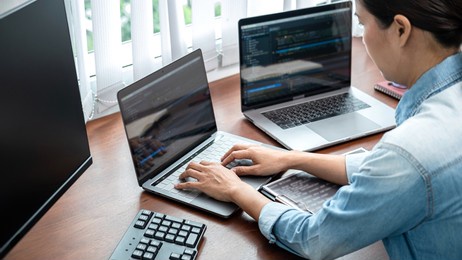 asian programmer woman looking on multiple computer screen to typing coding database and development website or applications while working about new project in software development office
