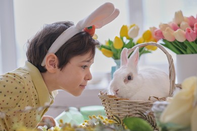 happy easter. child boy in bunny ears and hare sits in a wicker basket for spring holiday celebration. soft focus