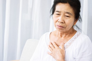 old asian woman having problem with shortness of breath, difficult breathing hand touching her chest 