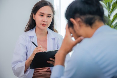 asian woman professional psychologist doctor write, note on paper and giving the consult to man patients in room of house or hospital exam room, mental health concept, doctor of advisors concept