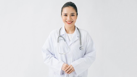 happy beautiful female doctor in medical coat standing with crossed arms isolated on white
