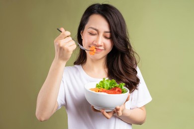 cheerful young asian girl eating health food on background