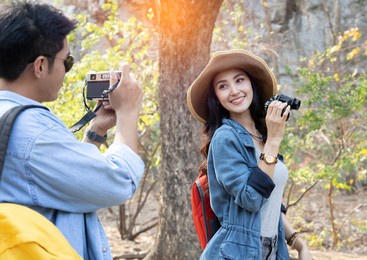 beautiful asian woman traveller smiling to her boyfriend's camera while travelling in forest