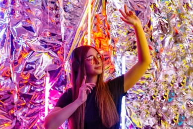 a young, attractive woman wearing headphones listens to music in the neon night light. girl dj. creative portrait in neon lighting. the concept of youth culture.