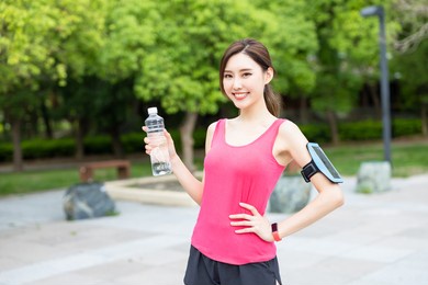 asian sport woman with transparent plastic bottle and smile at you in the park