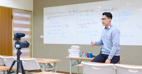 asian male professor teach calculus online through camera in classroom