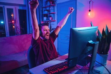 young man plays computer games at home.  neon streamer studio. the guy with the headphones is having fun on the internet.