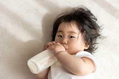 baby drinking milk with his own baby bottle (0 years old, 8 months old, japanese, girl)