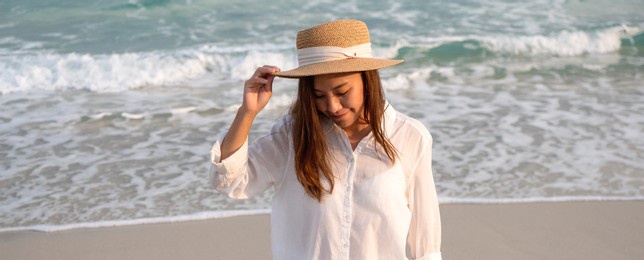 portrait image of a beautiful young asian woman strolling on the beach by the sea
