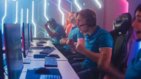 diverse esport team of pro gamers play in computer video game and win championship, celebrate with yes gestures. stylish design cyber games arena. online streaming of tournament. side view