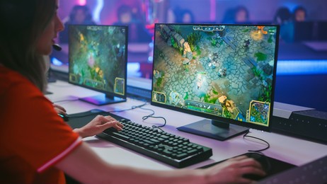 pro girl plays computer game plays rpg strategy on a championship. diverse esport team of pro gamers play in mock-up video game. stylish neon cyber games arena. over the shoulder shot