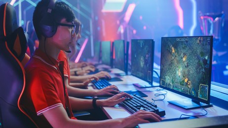 pro girl plays computer game plays rpg strategy on a championship. diverse esport team of pro gamers play in mock-up video game. stylish neon cyber games arena. side view