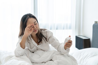 sleepy young asian woman wake up and turning off an alarm clock in the morning