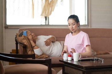 young asian daughter takes care of the senior mother who is sick in living room at home