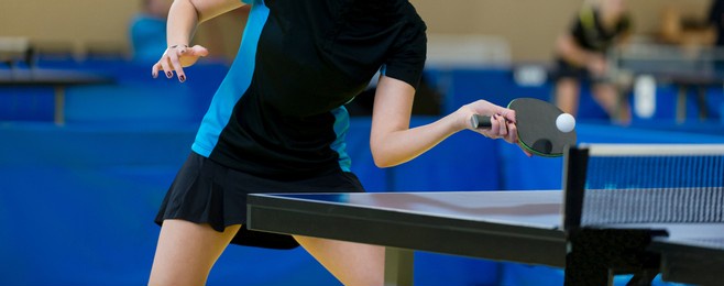 professional woman player playing table tennis with racket and ball in a sport hall