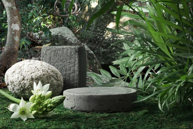 natural stone and concrete podium in tropical forest with flowers. empty showcase for packaging product presentation. background for cosmetic products, scene with green leaves. mock up pedestal.