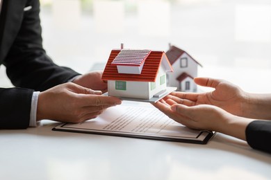 real estate broker agent presenting and consult to customer to decision making sign insurance form agreement, buy and sell home model, concerning mortgage loan offer for and house insurance
