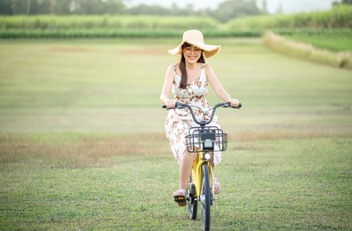 young beautiful asian woman riding a bicycle in a park. active people. pretty young woman riding bike in a country road.