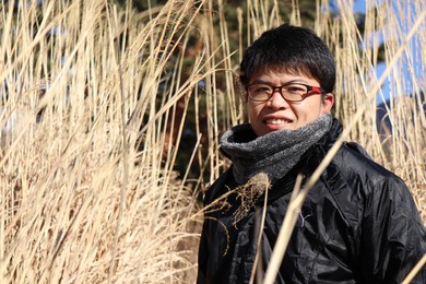asian man standing beside the tall grass in autumn with copy space