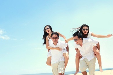 happy group of young friend doing piggyback together at the beach in summer day