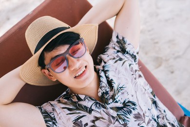asian man lying resting on the beach
