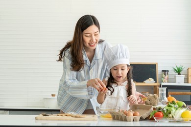 young girl and daughter learned to cook breakfast with mom. a beautiful asian woman was happy in the kitchen at home. 