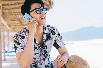 young asian man using smartphone on the beach