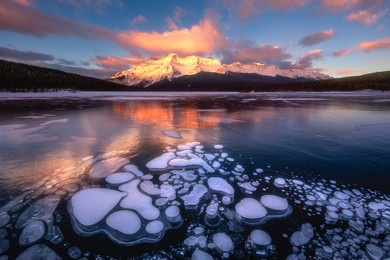 ice bubbles on the surface of the blue ice. frozen lake in winter mountains. minnewanka lake, alberta, canada