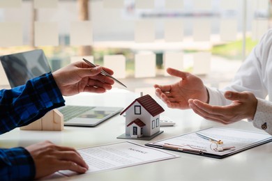 the real estate agent is explaining the house style to the clients who come to contact to see the house design and the purchase agreement, mortgage loan approval home loan and insurance concept.