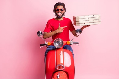 portrait of handsome cheery amazed guy riding moped delivering demonstrating pizza advert isolated over pink pastel color background