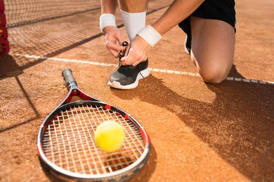 unrecognizable tennis player tying shoelaces while playing