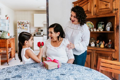latin grandmother woman with daughter or grandchild celebrating birthday, 8 march international women holiday or happy mother's day in mexico city
