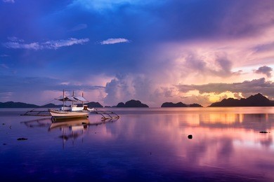 tropical sunset with a banca boat in el nido, palawan - philippines. 