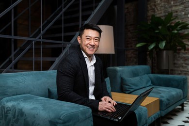 successful asian businessman, in a black business suit, works on a laptop, relaxes in a restaurant or hotel, and in a stylish office explains a new business strategy via video link