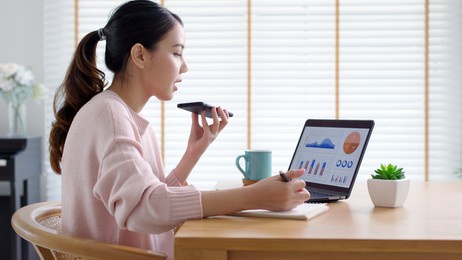young happy attractive beautiful asia female talk on mobile phone sit work on desk table at home. remotely work reskill upskill on distance job or data analysis sale report for business intelligence.