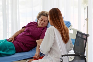 elderly asian woman are patient on bed with woman doctor sitting doing examination old woman in examination room at hospital in the morning.