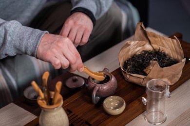 men's hands put special bamboo clip tea leaves in a ceramic teapot made of yixing tray. the process of making chinese tea.