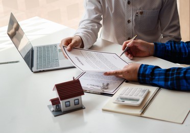 buying a home or insurance, an insurance agent explains the lease agreement to a client before making a contract. mortgage loan approval home loan and insurance concept.

