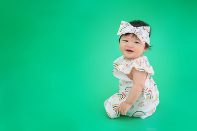 asian happy cute baby smiling, sitting on green background. 6 months baby with copy space as concept of bedroom, development, health, mood and motion of baby and kid department in hospital